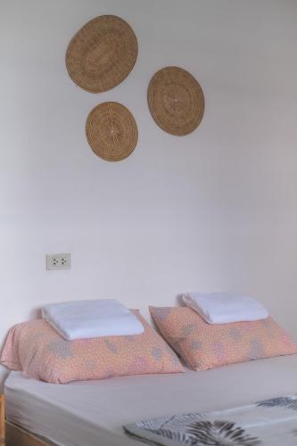 a bed with two pillows and three hats on the wall at BOHO Hostel in Ko Lanta