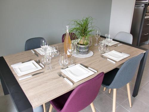 une table en bois avec des assiettes et des verres à vin dessus dans l'établissement Cottage du Phare, 3 chambres & jardin, classé 3 étoiles, à Cayeux-sur-Mer