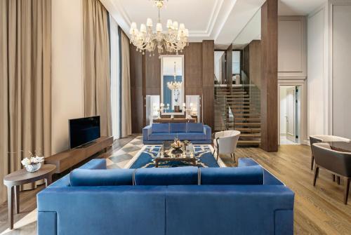 a living room with blue couches and a chandelier at Kaya Palazzo Resort & Casino in Kérynia