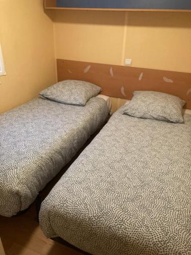 2 nebeneinander sitzende Betten in einem Schlafzimmer in der Unterkunft Mobil-Home 2 "Camping" in Pesmes