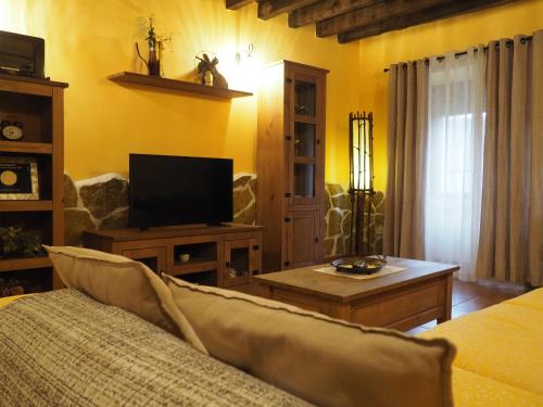 a living room with a couch and a tv at El Rincón de Anter C in Cenicientos