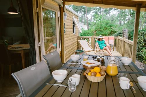 a woman sitting on a porch with a table with fruit at Naturéo in Seignosse