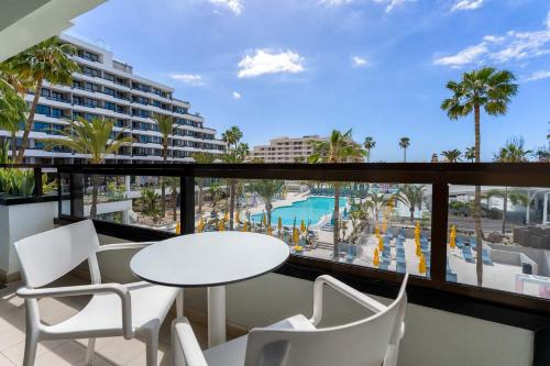 a balcony with a table and chairs and a view of a pool at Spring Hotel Bitácora in Playa de las Americas