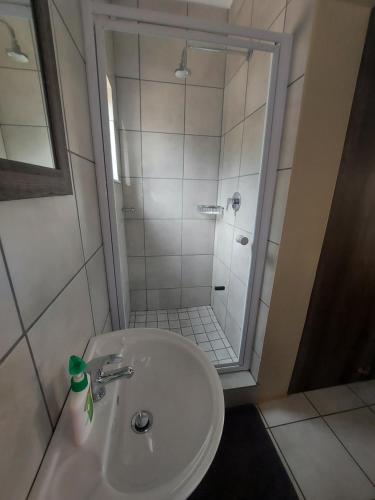 uma casa de banho com um chuveiro e um lavatório branco em DeLutz Overnight Accommodation Room 2 em Polokwane