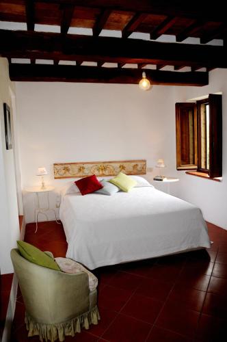 a bedroom with a large white bed and a chair at Agriturismo Naioli in Pitigliano