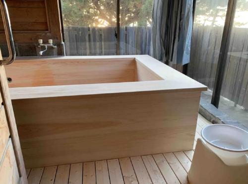 a large wooden bath tub in a bathroom with a toilet at 遙かな亭 in Numazu