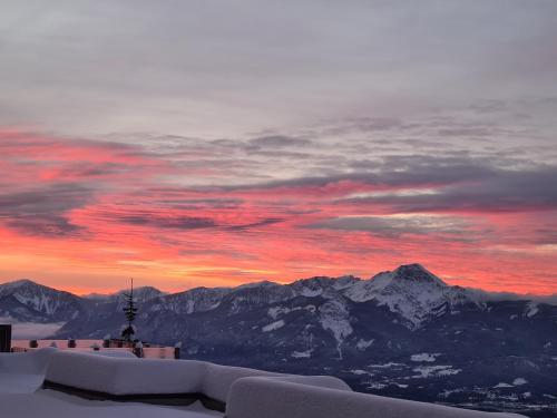 a sunset on top of a mountain with snowy mountains at Apartment Wanderlust Gerlitzen in Kanzelhöhe