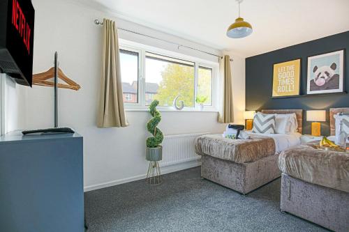 a bedroom with a bed and a couch and a window at Detached House - City Centre Location - Free Parking, Garden, Smart TVs with Netflix by Yoko Property in Milton Keynes