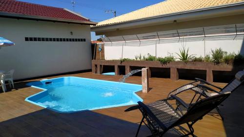 a patio with a swimming pool and two chairs at Recanto do Dan - Praia Picarras- Beto Carrero in Piçarras