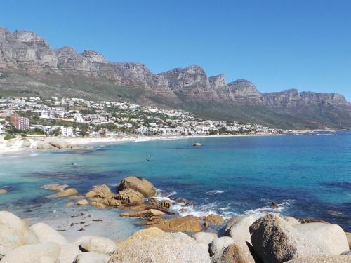 a beach with rocks and mountains in the background at South Beach Camps Bay Boutique Hotel in Cape Town