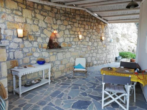 a room with a stone wall with a table and chairs at Tranquil Villa with Sea view in Ammopi Karpathos in Amoopi