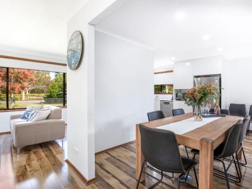 a dining room with a table and chairs and a clock at Sea and Sun Pet Friendly 4 Mins to Beach in Callala Beach