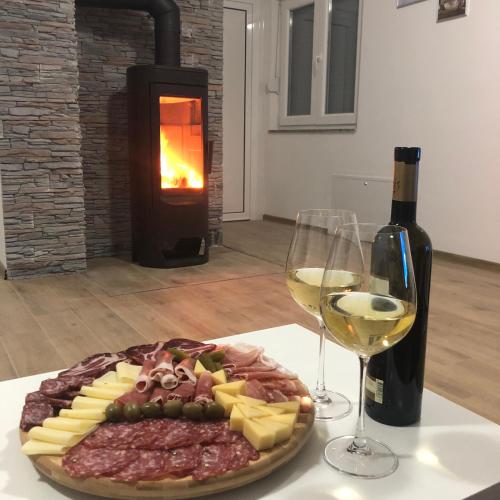 a plate of meat and cheese and a glass of wine at Vikendica Bruše in Jaklići