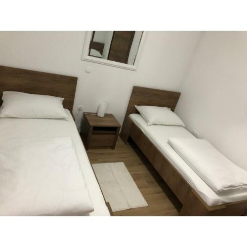 a bedroom with two beds and a night stand with a window at Vikendica Bruše in Jaklići