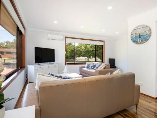 a living room with a couch and a tv at Sea and Sun Pet Friendly 4 Mins to Beach in Callala Beach