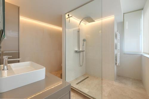 ein Badezimmer mit einem weißen Waschbecken und einer Dusche in der Unterkunft Luxury 3 Bedroom Beach Front Apartment in Marbella in Marbella
