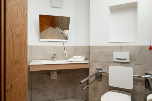 a bathroom with a sink and a toilet and a mirror at Dorfstube in Holzgau
