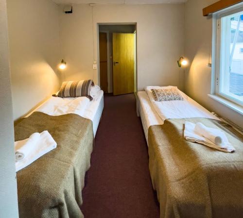 2 Betten in einem Zimmer mit Fenster in der Unterkunft Hotell Nesbyen in Nes i Ådal