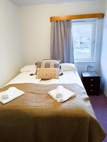 1 cama con 2 toallas y ventana en Hotell Nesbyen, en Nes i Ådal