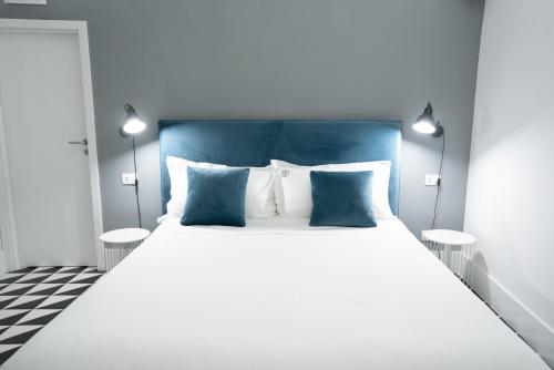una camera da letto con un grande letto con cuscini blu e bianchi di Pulcinella Suite a Napoli