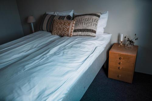 ein großes Bett mit Kissen und einem Nachttisch in der Unterkunft Hotell Nesbyen in Nes i Ådal