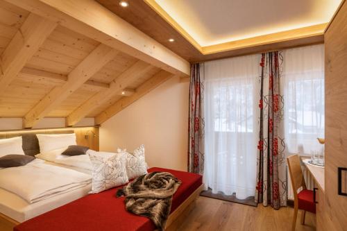 a bedroom with a large bed and a large window at Dorfstube in Holzgau