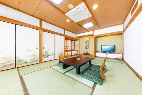 a living room with a table and a tv at Umino Hotel Hajime in Beppu