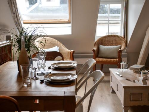 une salle à manger avec une table et des chaises en bois dans l'établissement L'appart de la Ferté - Rue principale de St Valery, à Saint-Valery-sur-Somme