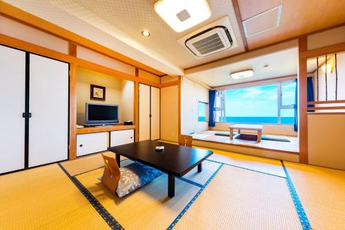 a living room with a table and a tv at Umino Hotel Hajime in Beppu