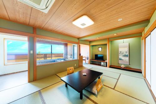 a living room with a table and a large window at Umino Hotel Hajime in Beppu