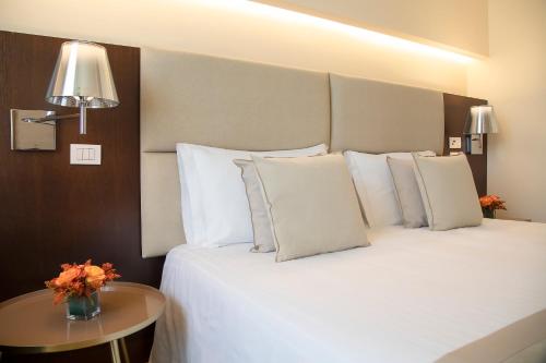 a bedroom with a bed with white pillows and a table at La Reggia Sporting Center Hotel in Cascia