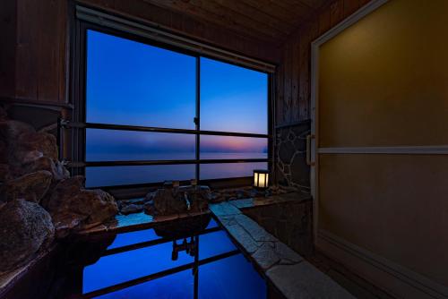 a room with a large window with a reflection in the water at Umino Hotel Hajime in Beppu