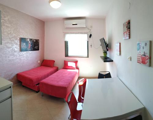 een woonkamer met 2 rode bedden en een bank bij Hotel Apartment Short Term Tel Aviv Bat Yam 353 in Bat Yam
