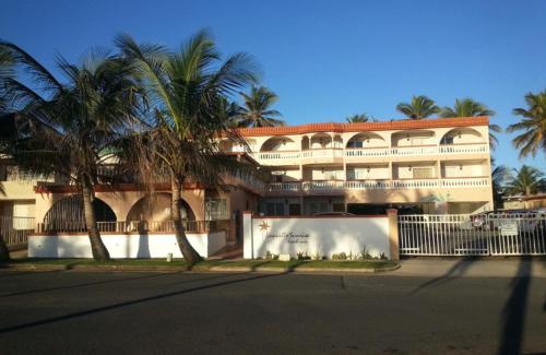 a large building with palm trees in front of it at Luquillo Sunrise Beach Inn in Luquillo