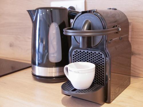 - une cafetière avec une tasse sur un comptoir dans l'établissement Le studio de la Ferté - Rue principale St Valery, à Saint-Valery-sur-Somme