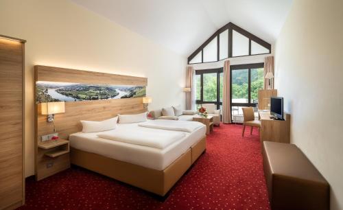 een slaapkamer met een groot bed en een woonkamer bij Hotel Moselblick in Winningen