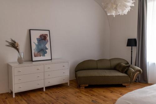 a bedroom with a chair and a dresser with a picture at FAJRONT - krásny historický byt v srdci Kremnice in Kremnica