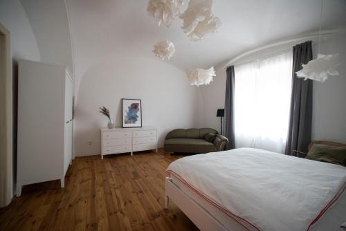 a white bedroom with a bed and a window at FAJRONT - krásny historický byt v srdci Kremnice in Kremnica
