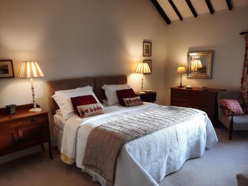 a bedroom with a bed with two lamps and two tables at The Shippon, Parc yr Odyn, Pentraeth, Anglesey LL75 8UL in Pentraeth
