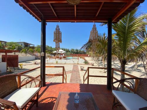 un patio con una mesa y sillas y una playa en El Samay Hotel Boutique, en Canoas de Punta Sal