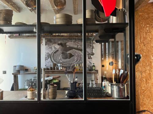 une armoire en verre avec des casseroles et des poêles dans la cuisine dans l'établissement Maison rivière très calme près de Chablis et Noyers sur serein chez un céramiste designer, à Annay-sur-Serein