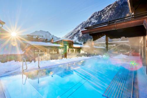a swimming pool with snow covered mountains in the background at Hotel Neue Post in Mayrhofen