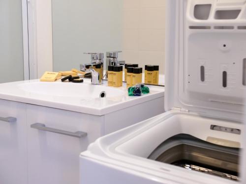 une cuisine blanche avec un évier et un micro-ondes dans l'établissement Maison neuve lumineuse avec jardin, parking privé, à Saint-Valery-sur-Somme