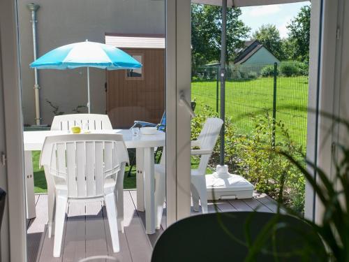 un patio avec une table, des chaises et un parasol dans l'établissement Maison neuve lumineuse avec jardin, parking privé, à Saint-Valery-sur-Somme