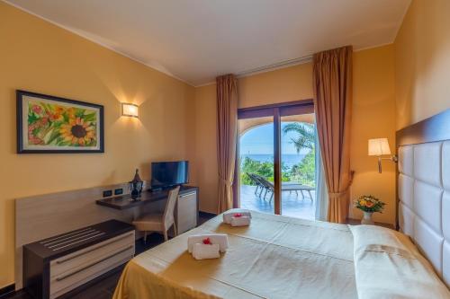 a hotel room with a bed and a desk and a window at Hotel Cannamele Resort in Parghelia