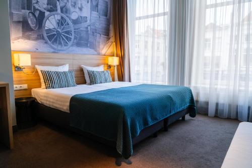 a bedroom with a large bed and a large window at Stadshotel De Klok in Breda