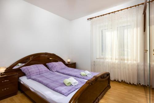 una camera da letto con un letto con cuscini viola e una finestra di Apartments Meri a Sveti Ivan