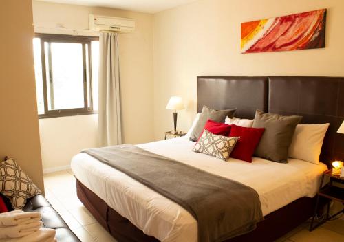 1 dormitorio con 1 cama grande con almohadas rojas en Uvas Apart Hotel en Mendoza