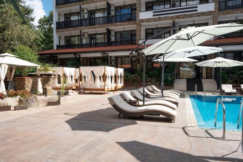 a pool with lounge chairs and umbrellas next to a building at The Green Paradise Apartments in Primorsko
