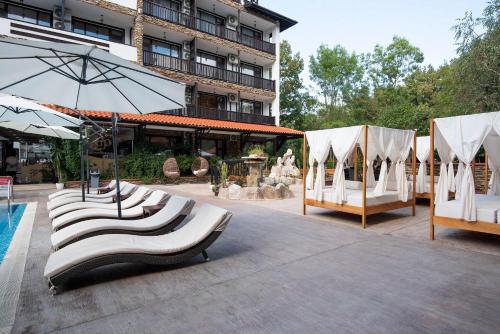 a group of white chairs and umbrellas next to a building at The Green Paradise Apartments in Primorsko